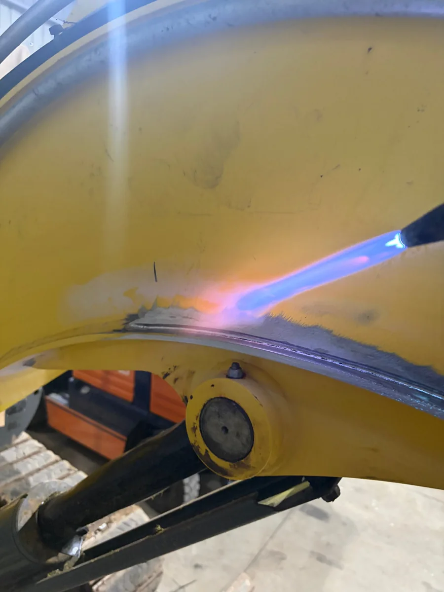 Oxy-acetylene torch preheating the repair area on an excavator boom in the Golden Square workshop, before MIG welding