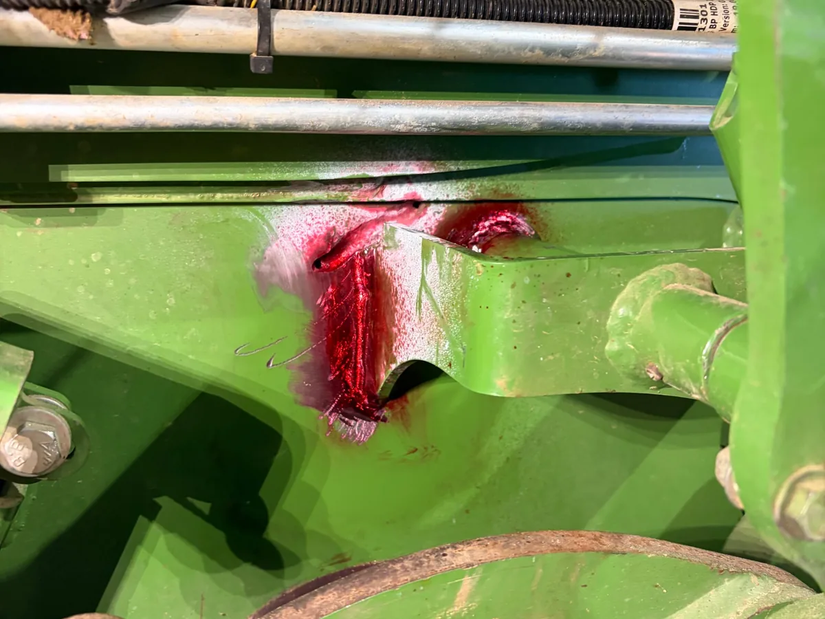 Close-up of red dye in a crack beside the bracket on a hay baler near Prairie