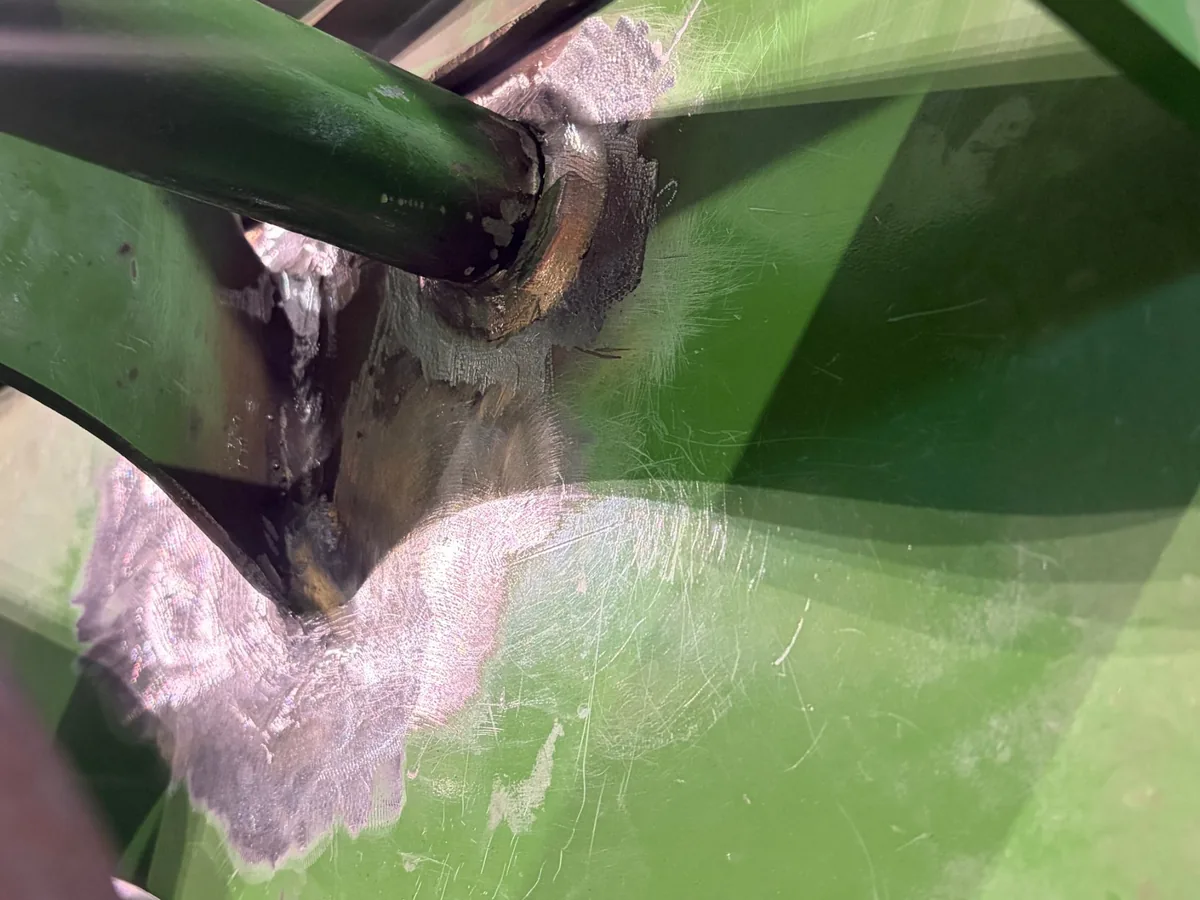 Close-up of the finished welds around the pin and bracket on a hay baler near Prairie